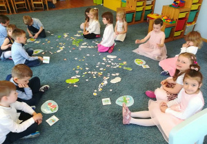 Dzieci siedzą na dywanie układają z sylwet wg wzoru sałatkę warzywną dla mamy.